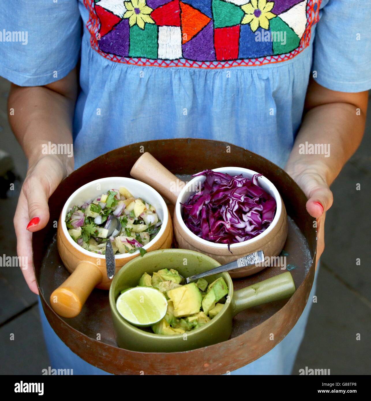 La donna che serve una selezione di piatti di salsa messicana Foto Stock