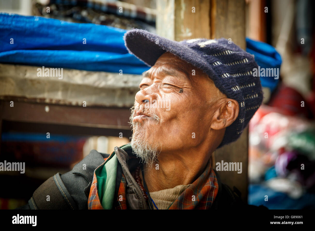 Il vecchio uomo bhutanesi facendo una faccia e guardando lontano dalla telecamera Foto Stock