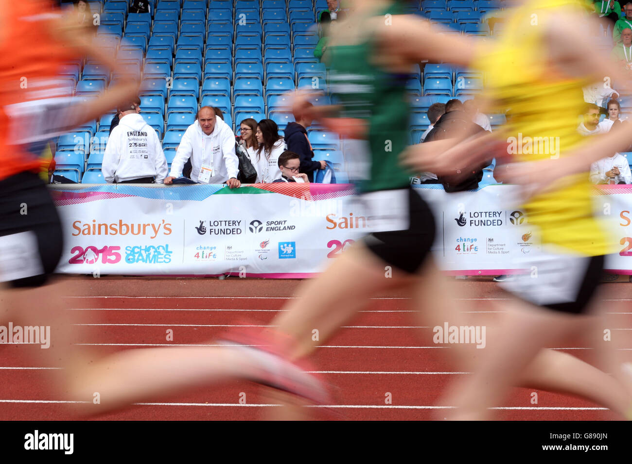Le ragazze 3000m runner si fanno strada oltre la folla di tifosi ai Sainsbury's 2015 School Games presso la Manchester Regional Arena. Foto Stock