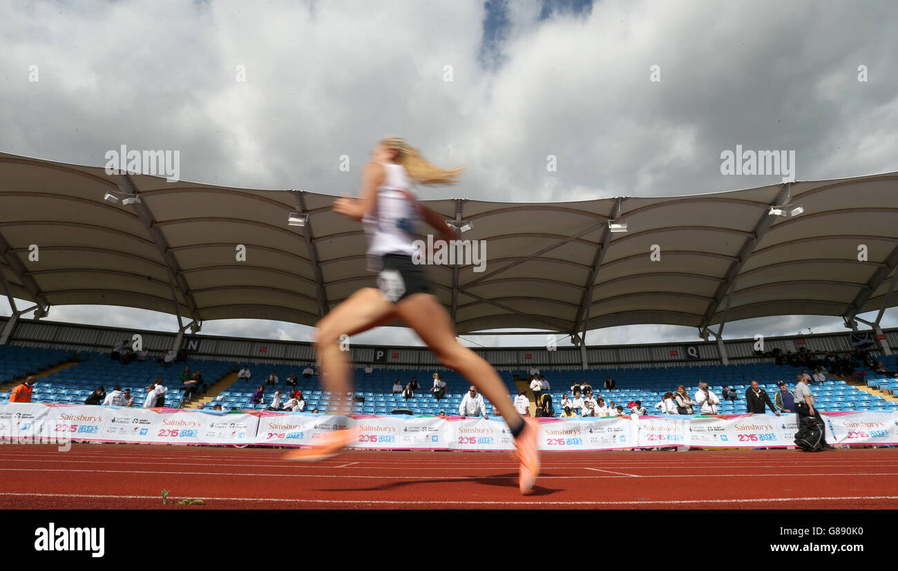Le ragazze 3000m runner si fanno strada oltre la folla di tifosi ai Sainsbury's 2015 School Games presso la Manchester Regional Arena. Foto Stock