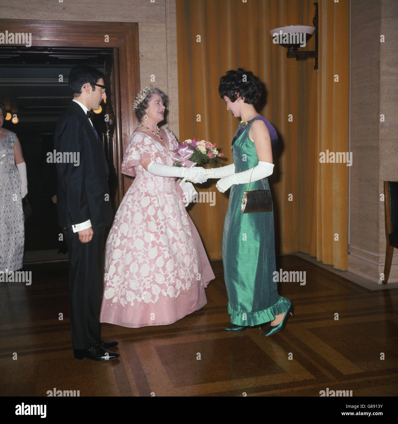 La Regina Elisabetta la Regina Madre ha ricevuto un bouquet da Elspeth Earle, Presidente del Women's University Sports Committee, quando ha partecipato al Presidente di Union's Dinner and Ball alla Camera del Senato dell'Università di Londra. Il Presidente dell'Unione, Drummond D. A. Leslie, è raffigurato a sinistra. Foto Stock