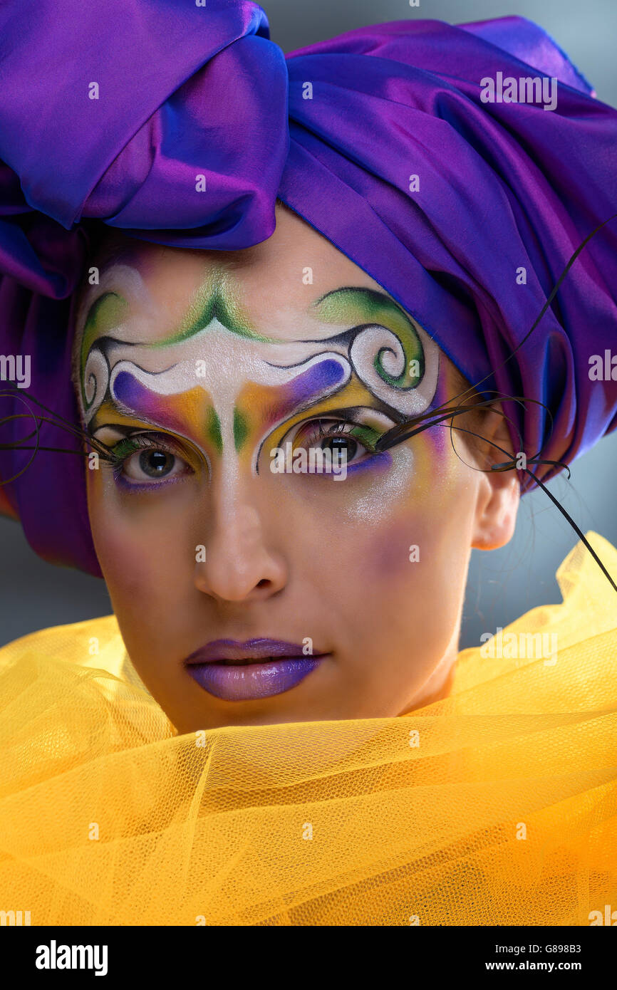 Modello femminile ritratto con creative tribali per il make-up e di turbolenza viola turbante, tulle giallo Foto Stock