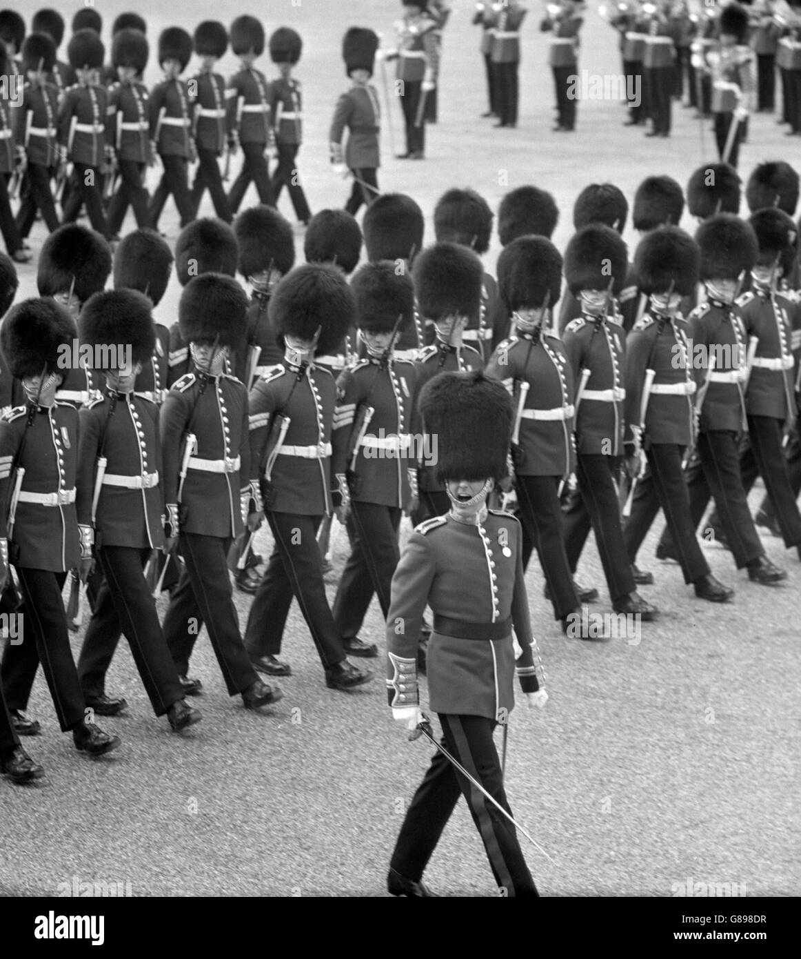 Con precisione a orologeria, le teste scattano a destra mentre un ufficiale mantice l'ordine quando le guardie passano la base di saluta durante una prova di Trooping the Colour su Horse Guards Parade a Londra. La cerimonia, in onore del compleanno della Regina, si svolge l'11 giugno. Foto Stock