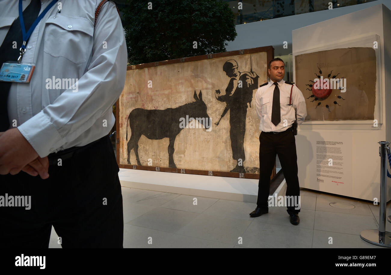 Le guardie di sicurezza si trovano accanto al 'Donkey Documents' di Banksy, un murale intatto di quattro tonnellate da Gerusalemme, nel Design Center di Chelsea, Londra. Foto Stock