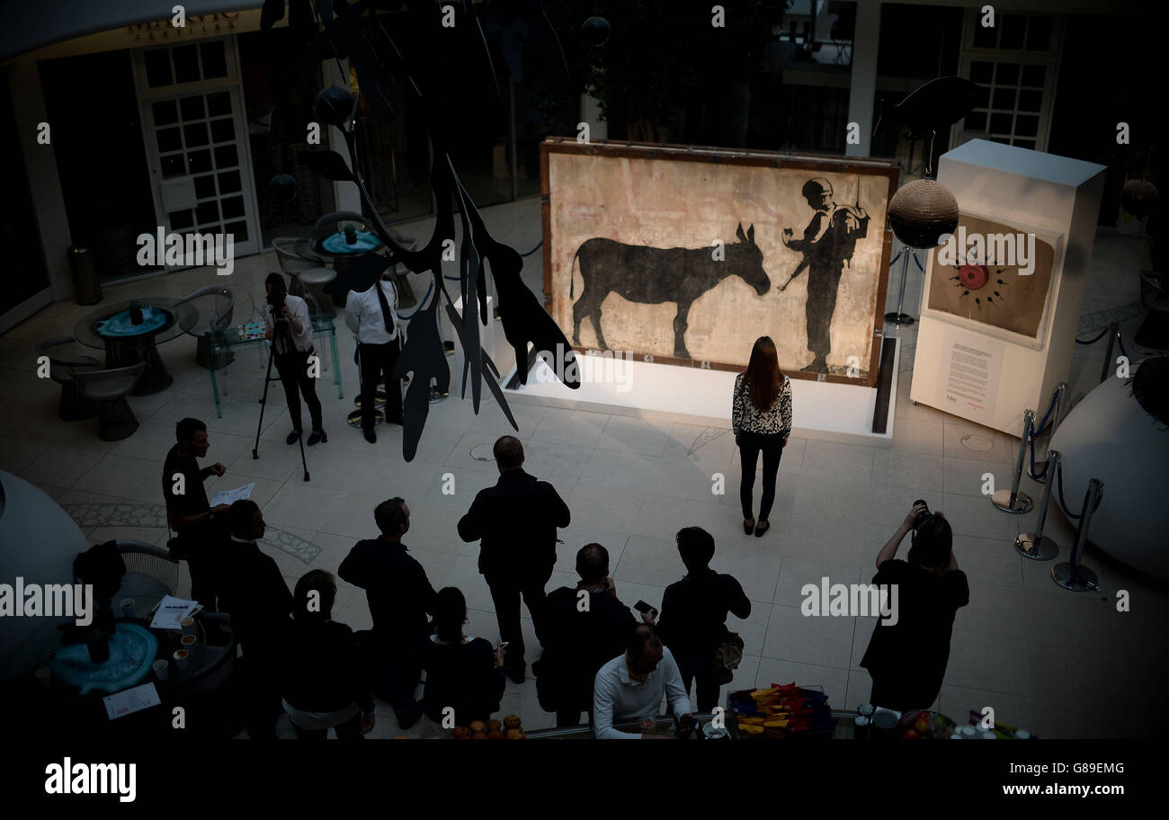 Una donna vede il 'Donkey Documents' di Banksy, un murale intatto di quattro tonnellate da Gerusalemme, nel Design Center a Chelsea, Londra. Foto Stock