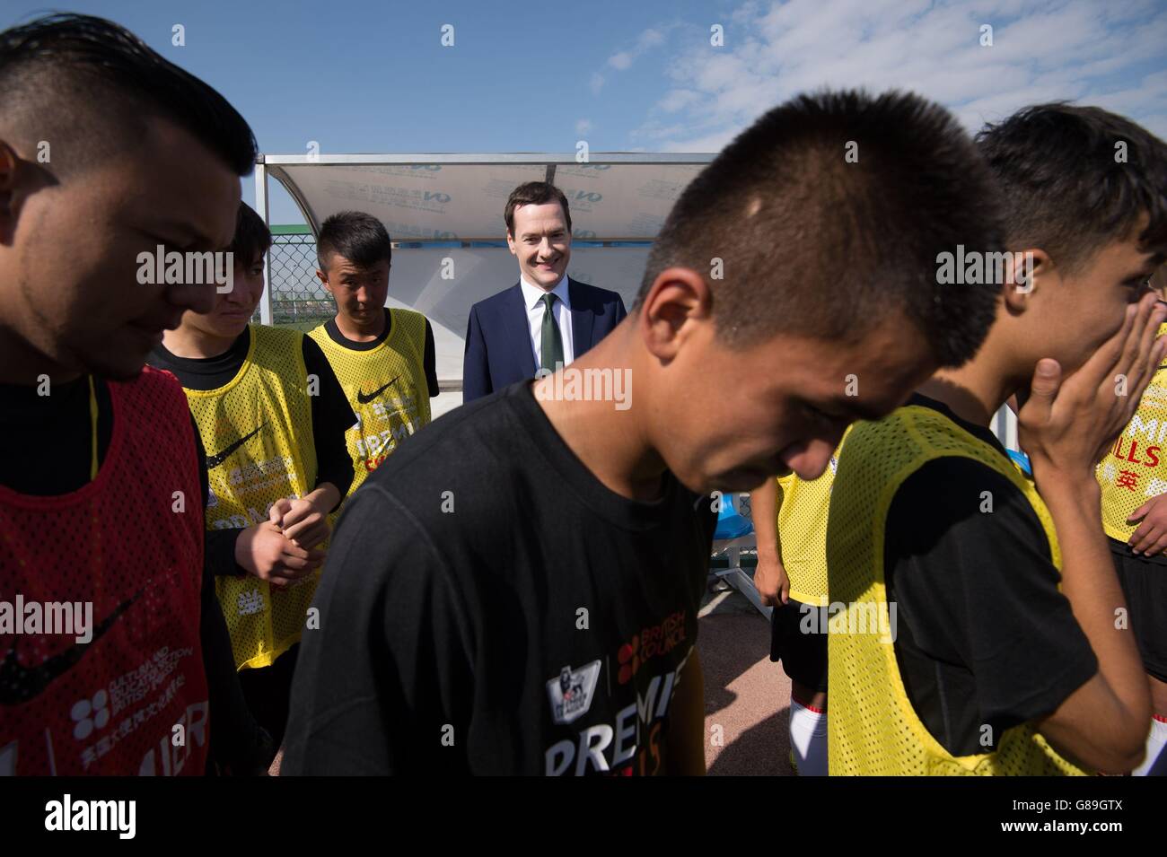 Il Cancelliere dello scacchiere George Osborne incontra giovani apprendisti calciatori alla Soong Ching Ling Football School nella città di Urumqi, Cina nord-occidentale, dove ha annunciato un &Acirc;&Pound; 3 milioni di finanziamenti per formare 5000 allenatori di calcio cinesi. Foto Stock