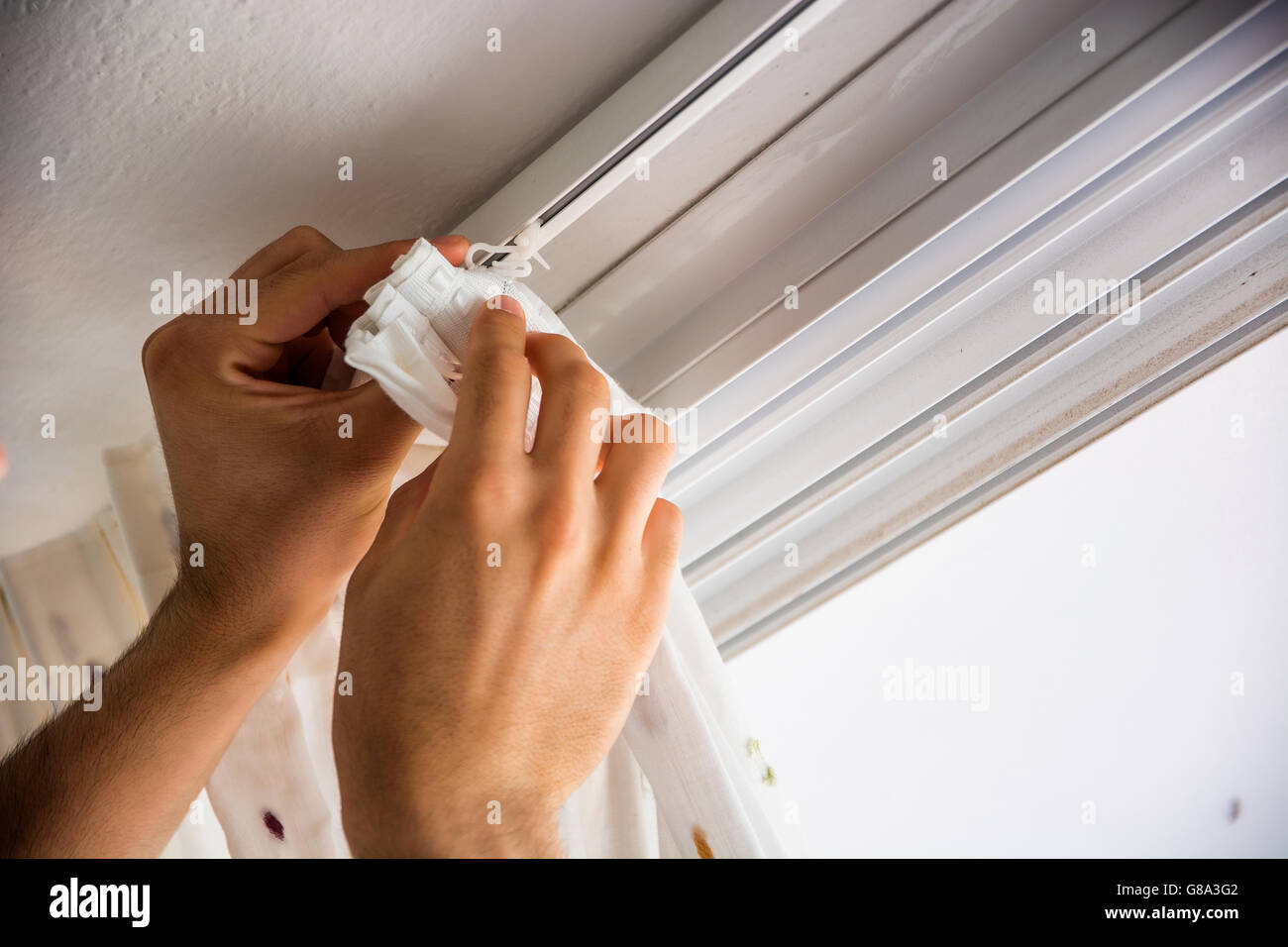 Le mani di uomo o tuttofare installazione tende alle finestre di casa, facendo lavori di rinnovo Foto Stock