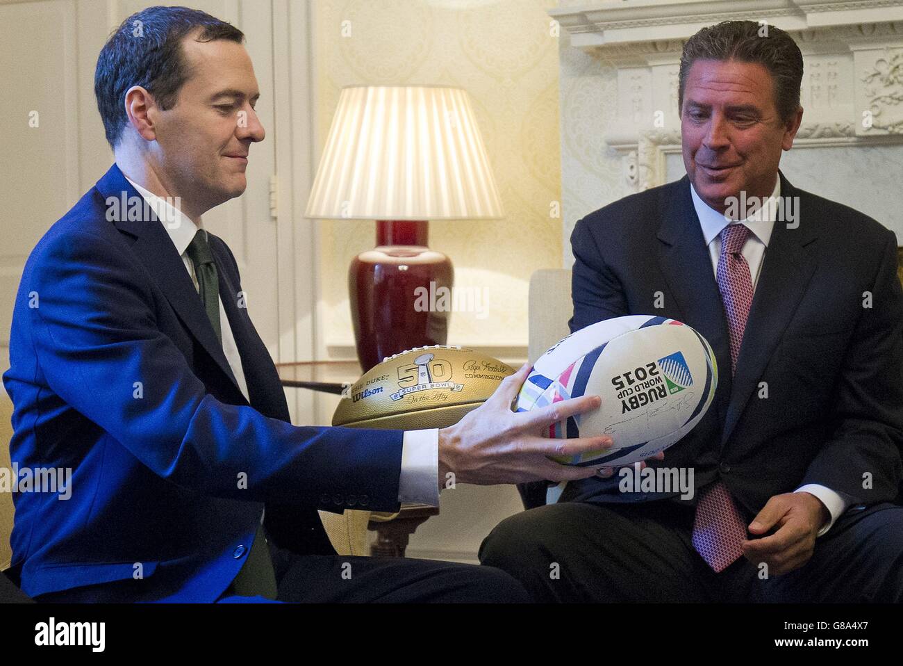 Il Cancelliere dello scacchiere George Osborne consegna una palla di rugby all'ex calciatore americano Dan Marino durante il loro incontro all'interno di 11 Downing Street a Londra prima dei Miami Dolphins incontrando i New York Jets allo stadio di Wembley la domenica. Foto Stock