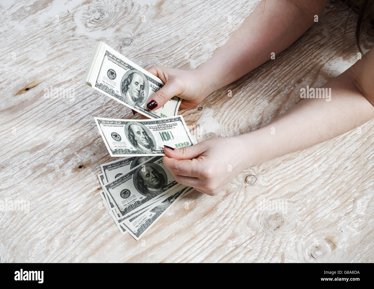 Donna con le mani di dollari su un sfondo di legno. Foto Stock