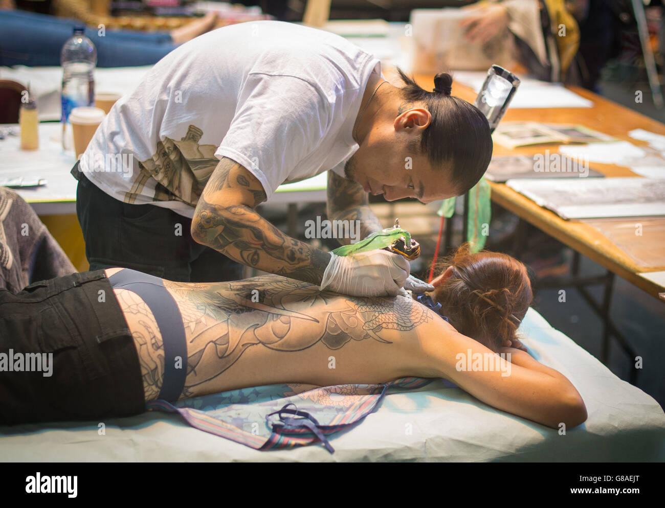 Un artista di tatuaggio al lavoro durante la London International Tattoo Convention, al Tobacco Dock, Londra. Foto Stock