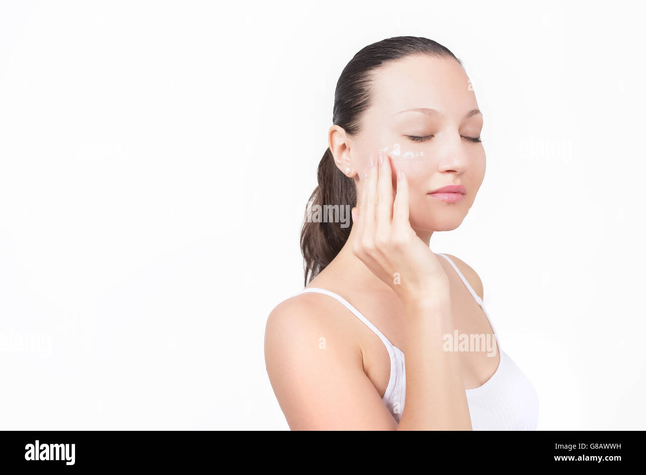 Close-up giovane bella faccia della ragazza applicando idratare la crema - isolato Foto Stock