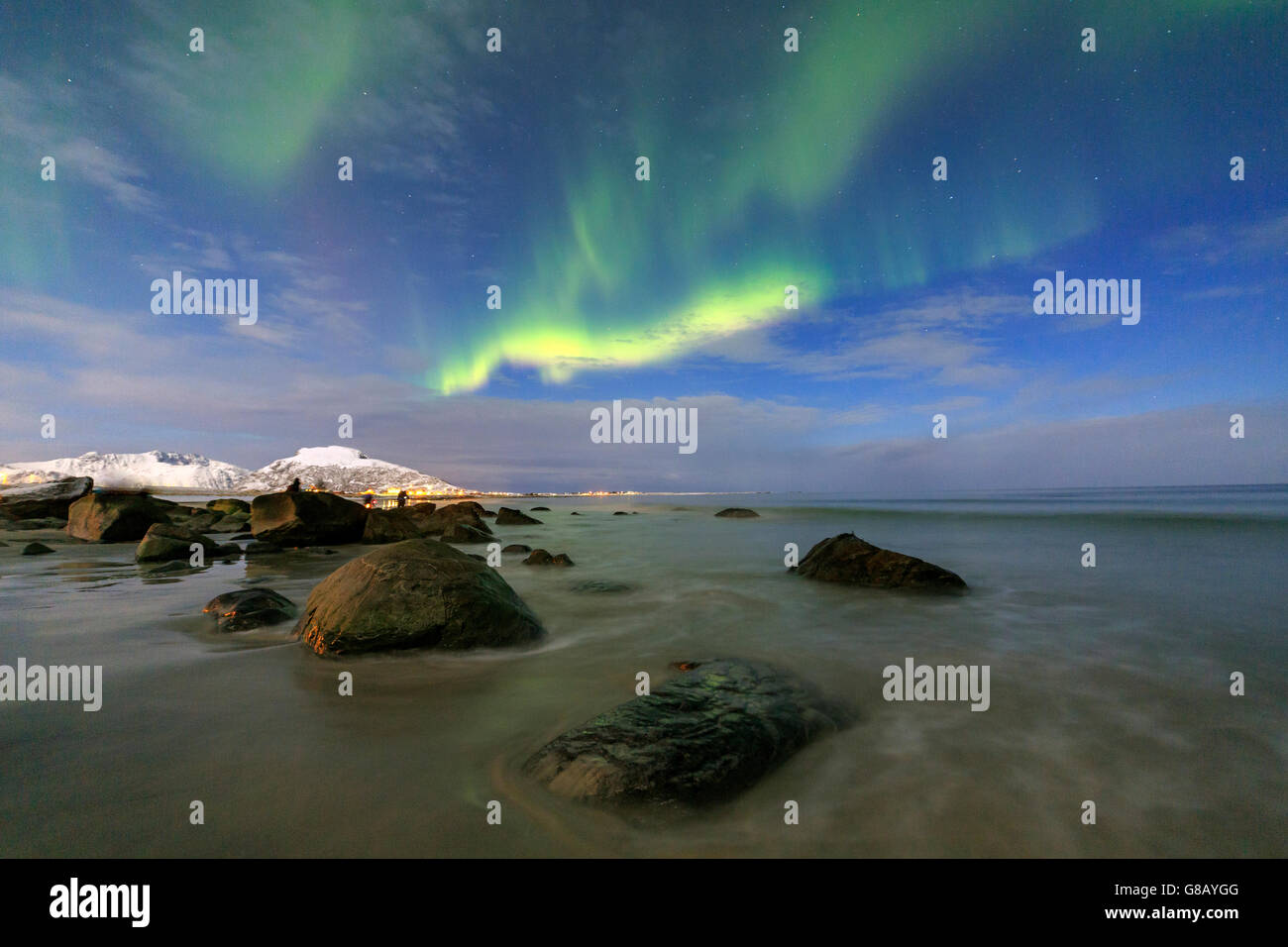 Northern Lights illuminano il paesaggio intorno Gymsøyand e le vette innevate delle isole Lofoten Norvegia del Nord Europa Foto Stock