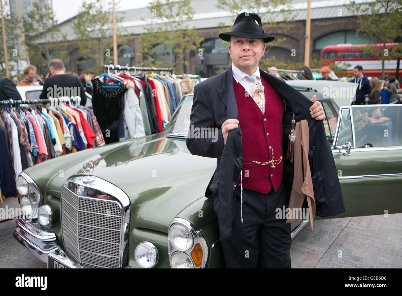 John Ball di Kent si pone davanti a una Mercedes-Benz 220SE d'epoca dal 1965 al Classic Car Boot sale di Lewis Cubitt Square, Londra. Foto Stock