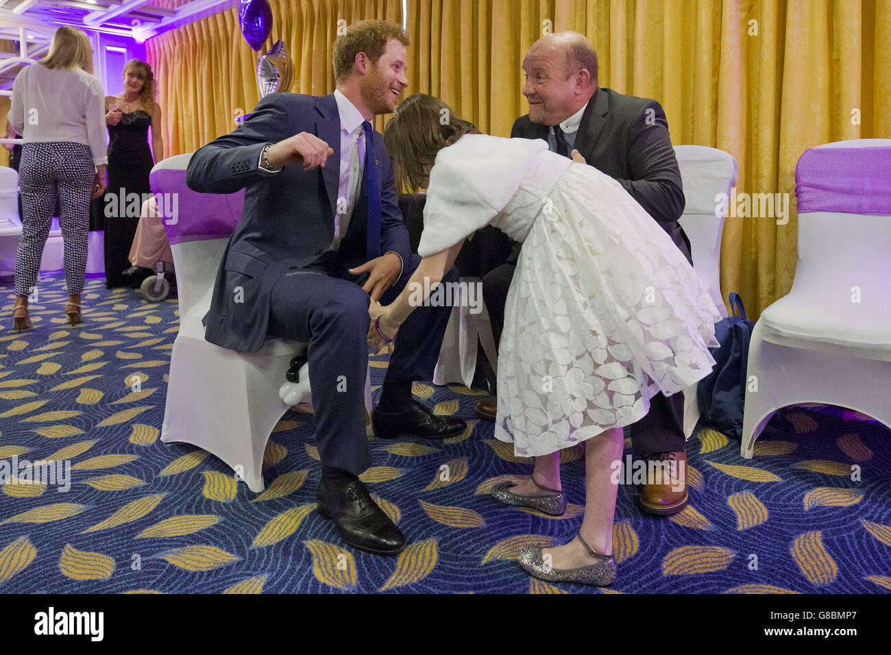 Il principe Harry incontra Nellie-mai Evans (centro), 9, vincitore del premio per giovani di ispirazione nel gruppo di 7-10 anni, e il padre adottivo Jeff (a destra), al WellChild Awards di Londra. Foto Stock