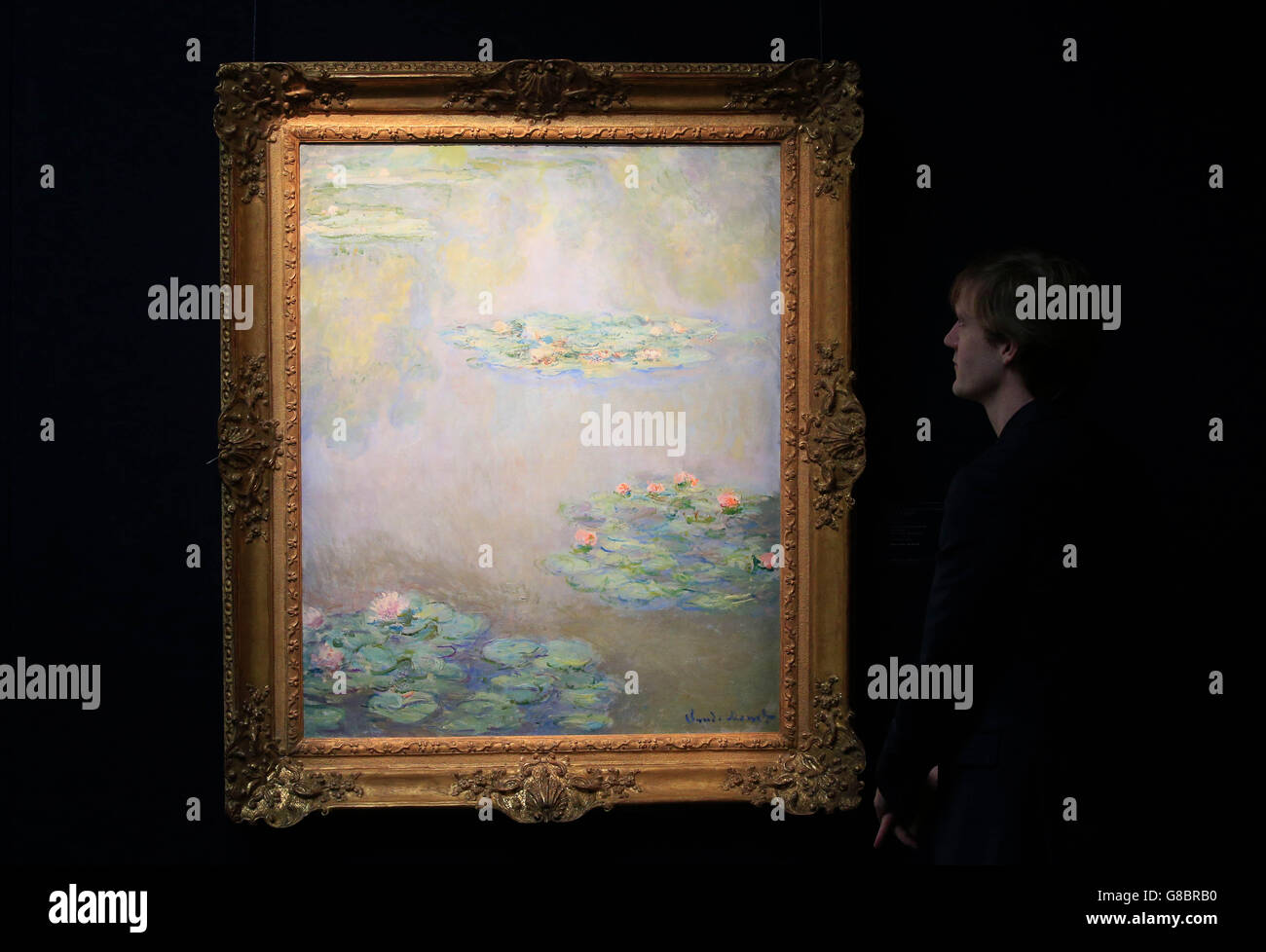 Un visitatore guarda il Nympheas di Claude Monet, dipinto intorno al 1908, durante un'anteprima stampa nel centro di Londra per la vendita serale di New York Impressionist e Modern Art. Foto Stock