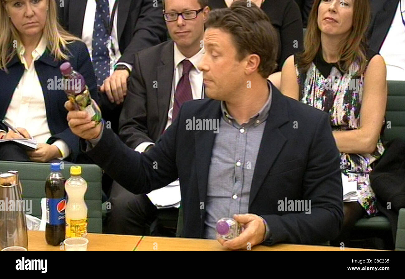 Il famoso chef Jamie Oliver tiene una bottiglia di bevanda analcolica mentre risponde alle domande di fronte al Comitato di selezione della Salute presso la Camera dei Comuni, Londra nel tema dell'obesità infantile. Foto Stock