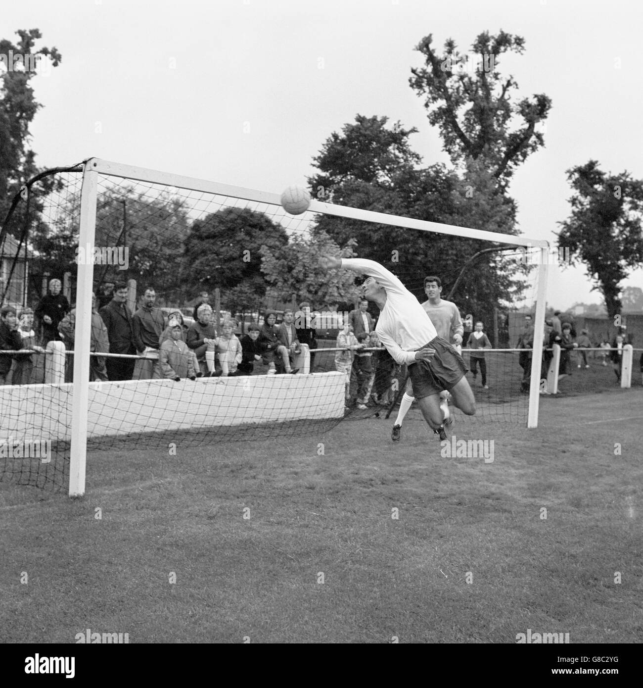 Jimmy Greaves, in Inghilterra, salta in balia mentre si stira in gol, guardato da un piccolo gruppo di fan e portiere Peter Bonetti (dietro Greaves) Foto Stock