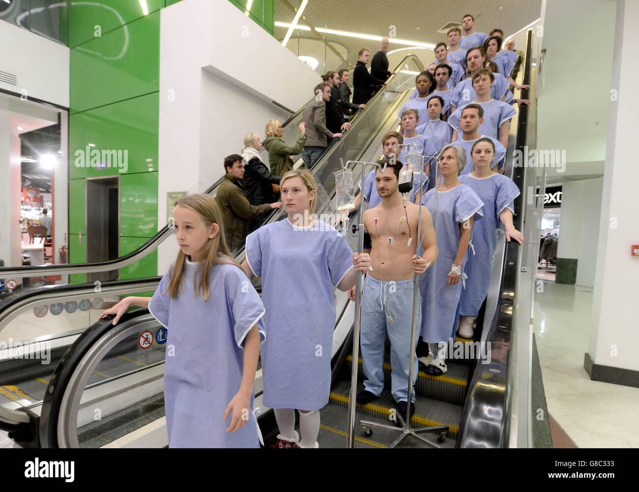 21 persone vestite di abiti chirurgici e di gocce di soluzione salina di spinta camminano tra pendolari a Victoria Station, Londra, per evidenziare il numero di pazienti britannici che muoiono ogni settimana in necessità di un trapianto di organo, in vista di una nuova serie documentaria Channel 5 chiamata il dono della vita. Foto Stock