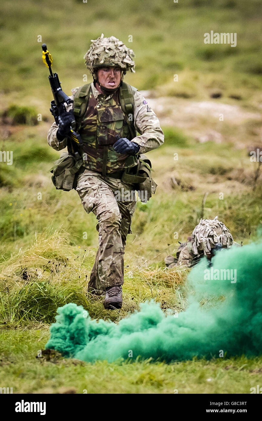 Un soldato dell'esercito britannico corre mentre fa un attacco durante una dimostrazione di manovra combinata delle armi su Salisbury Plain, Wiltshire. Foto Stock