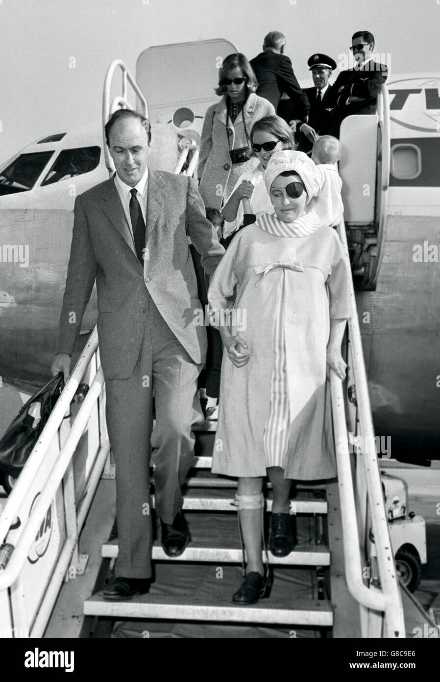 Torna a casa in Gran Bretagna è l'attrice Patricia Neal, vista accompagnata da suo marito, scrittore britannico Roald Dahl, come lei cammina giù i gradini dall'aereo all'aeroporto di Londra, al suo ritorno da Hollywood. La coppia era accompagnata dai loro tre figli, le figlie Tessa e Ophelia e il figlio Theo. Foto Stock