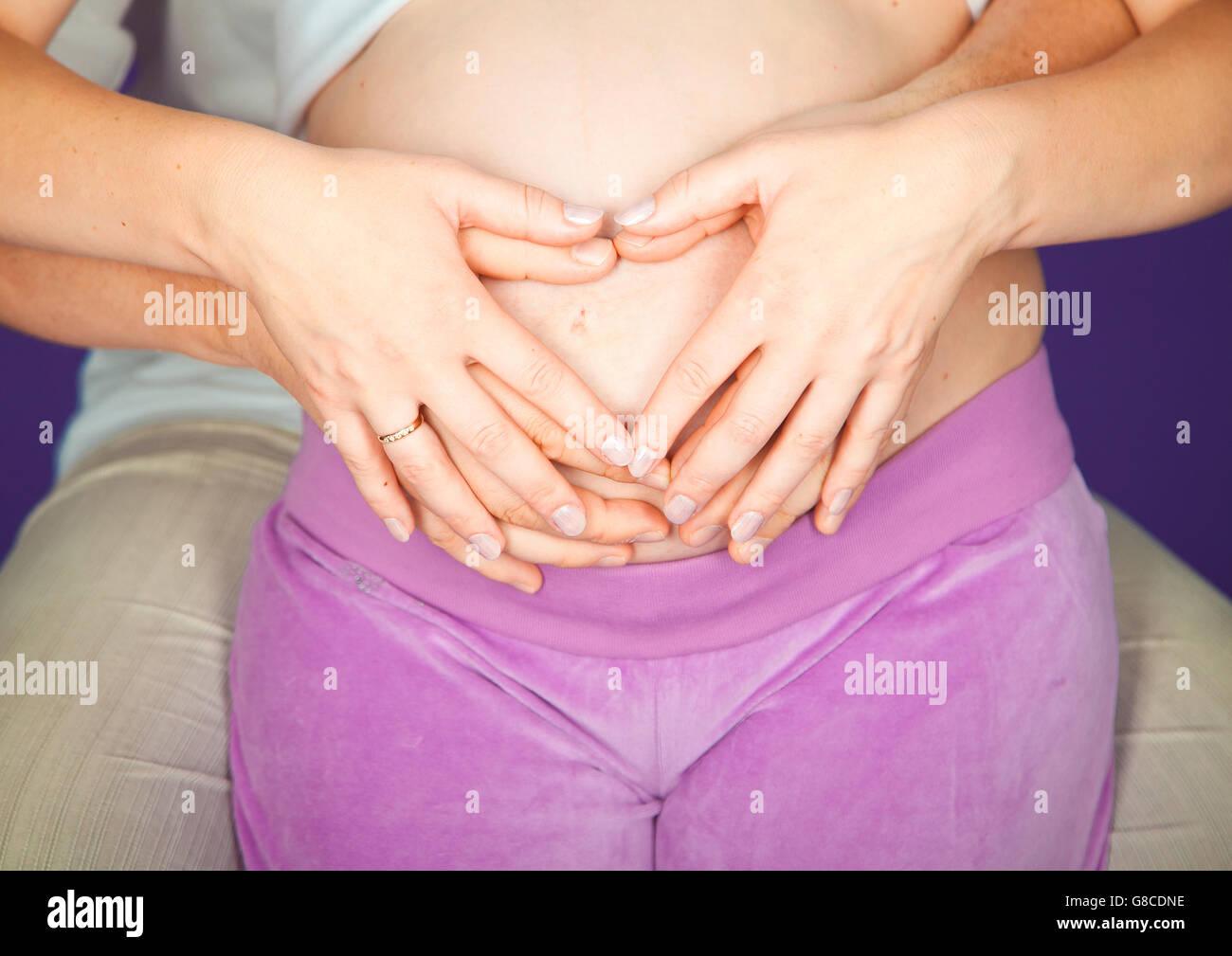 Madre in attesa tenendo piccolo cuore. Donna incinta tenendo le sue mani a forma di cuore sul suo bambino bump. Pancia in gravidanza con le dita il simbolo del cuore. Concetto di maternità. Baby doccia. Foto Stock