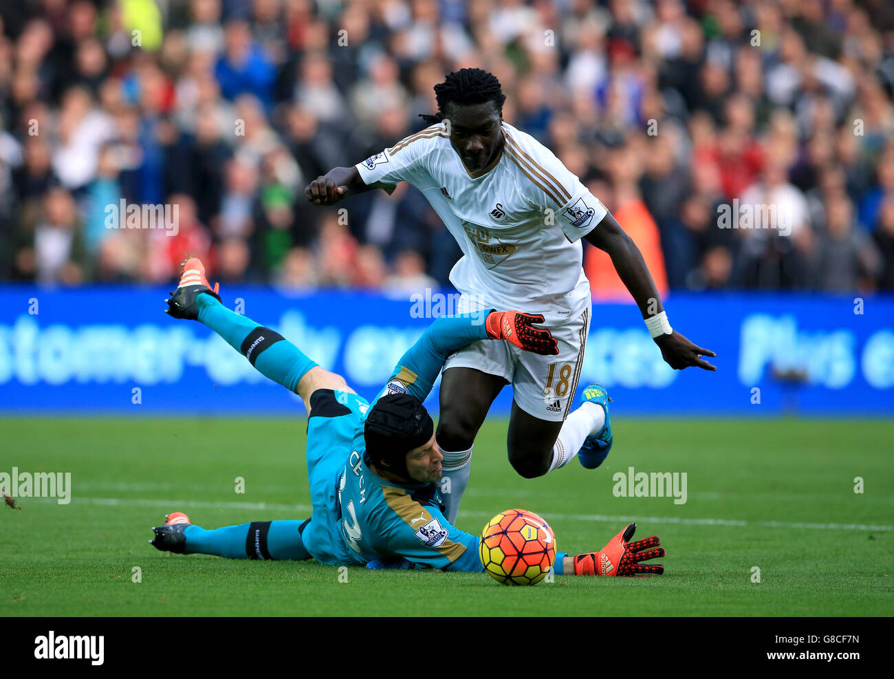 Il portiere dell'Arsenal Petr Cech si tuffa di fronte al Bafetimbi Gomis di Swansea City durante la partita della Barclays Premier League al Liberty Stadium di Swansea. Foto Stock