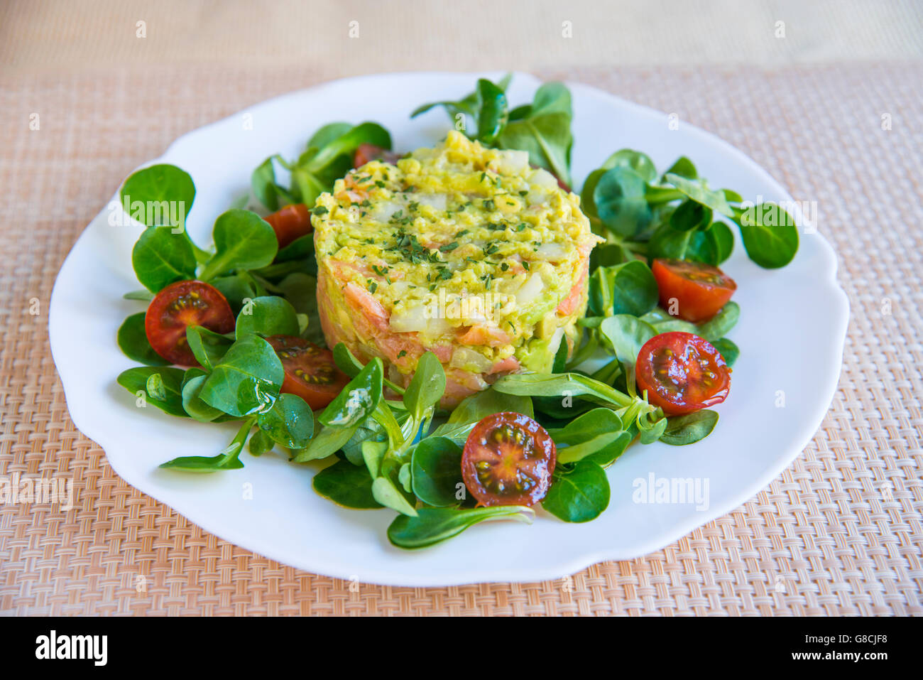 Salmone, avocado e cipolla torta con crescione e ciliegia insalata di pomodoro. Foto Stock