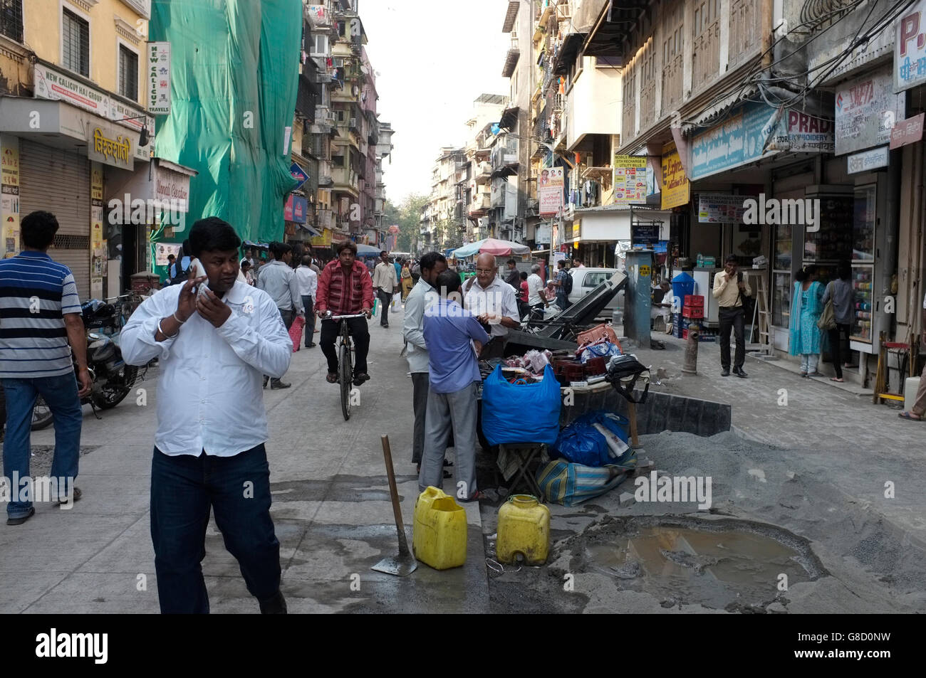 Un uomo parla di telefonia mobile in busy street scene, fort, Mumbai, India Foto Stock