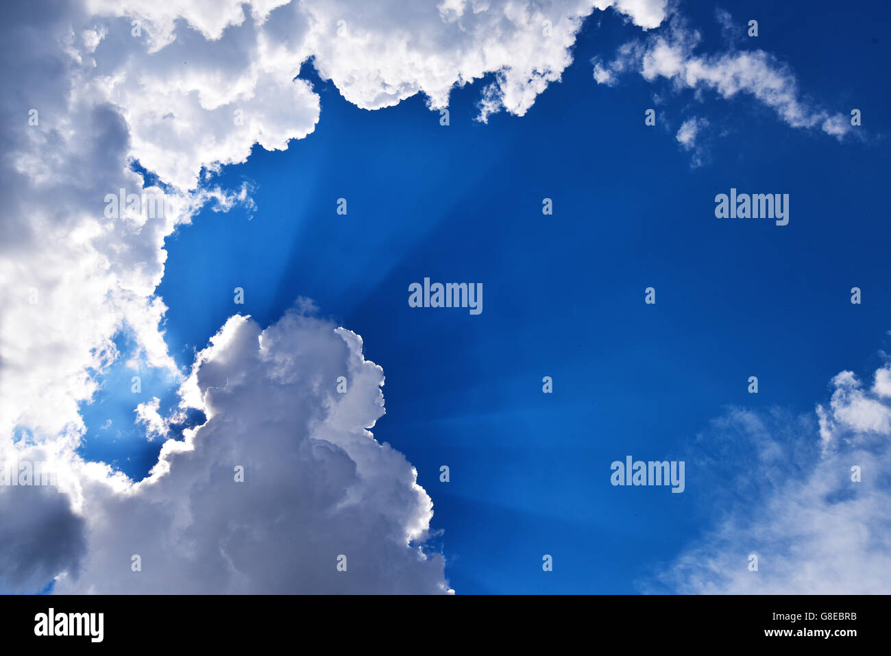 Raggi di sole e nuvole su un cielo blu Foto Stock