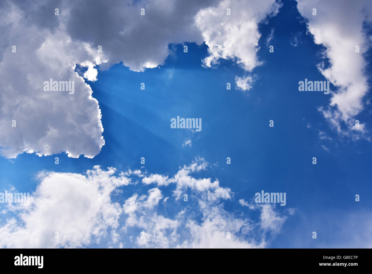 Raggi di sole e nuvole su un cielo blu Foto Stock