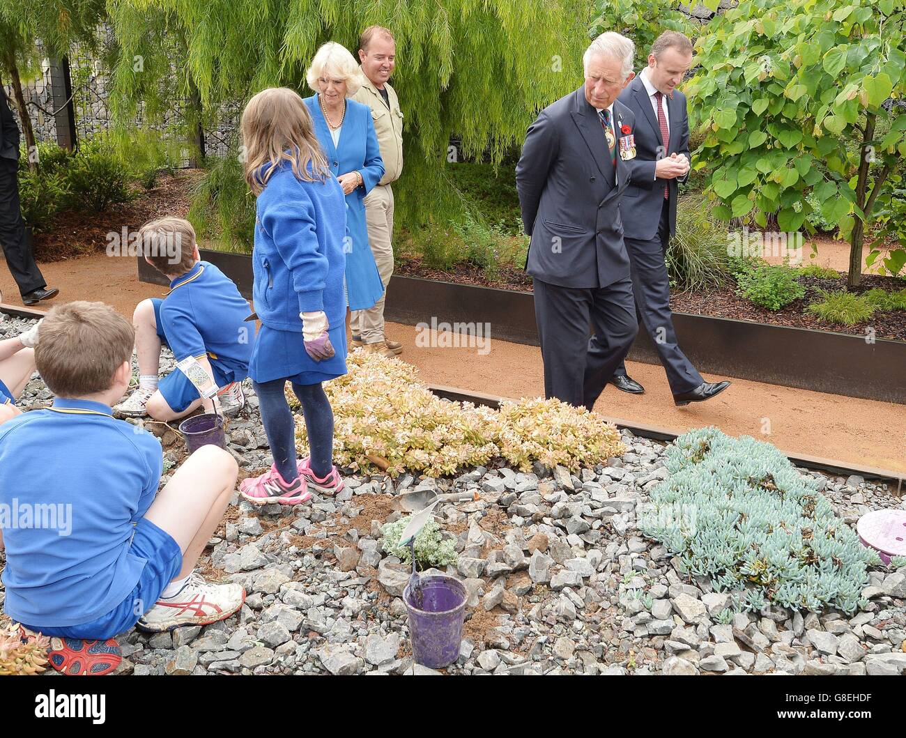 Il Principe di Galles e la Duchessa di Cornovaglia camminano accanto ai bambini che lavorano sui letti dei fiori, all'Arboreto Nazionale di Canberra, la capitale dell'Australia. Foto Stock
