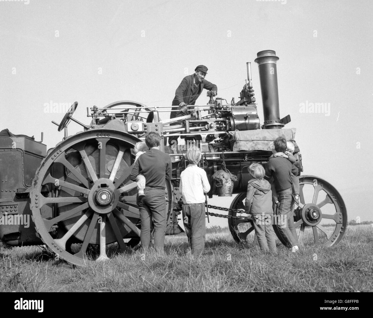 John Fieldgate e il suo giacinto affascinano un pubblico giovane a Marks Tey, Essex, dove il signor Fieldgate sta preparando un motore di trazione 1926 Marshall da 6 cv per un prossimo show. Il vecchio motore a vapore è mantenuto in perfetto ordine di funzionamento. Foto Stock