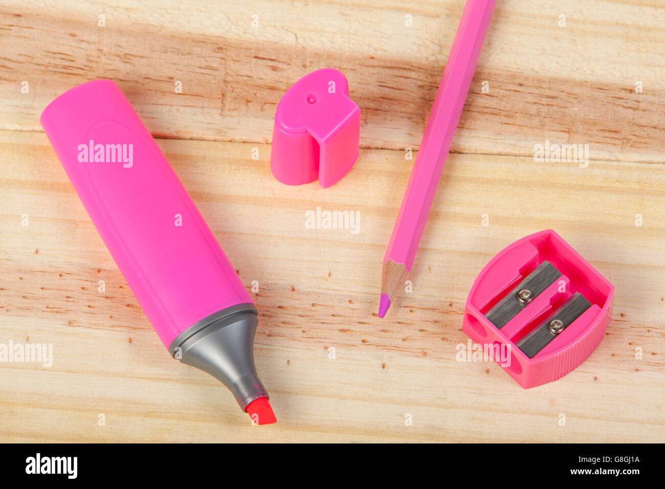 Colorazione rosa matita evidenziatore rosa e una rosa temperamatite posa su una scrivania in legno Foto Stock