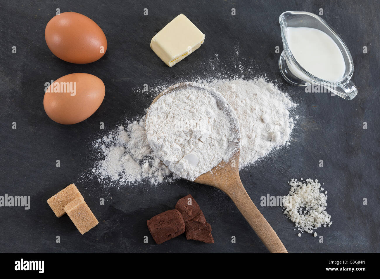 La cottura Ingredienti - farina, zucchero, uova, burro, cioccolato sulla tavola di ardesia. Vista dall'alto. Foto Stock