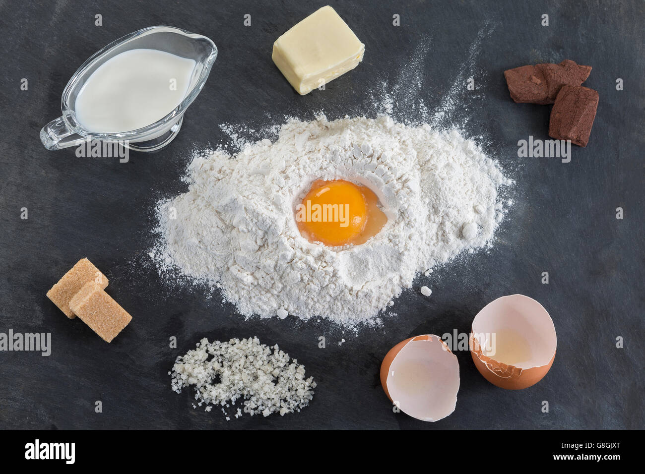 La cottura Ingredienti - farina, zucchero, uova, burro, cioccolato sulla tavola di ardesia. Vista dall'alto. Foto Stock