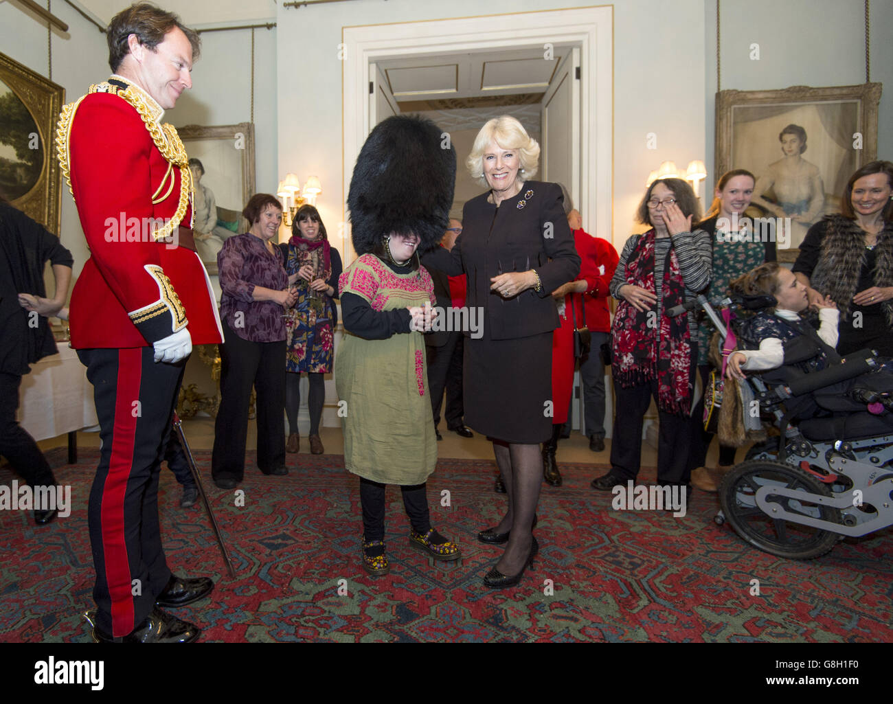 Alice Leigh prova su un cappello di pelle di bearskin che appartiene al capitano Matt Wright delle guardie gallesi (sinistra) mentre la Duchessa di Cornovaglia ospita un evento per decorare l'albero di Natale di Clarence House con l'aiuto di bambini sostenuti da Helen & Douglas House e dal London Taxi Drivers' Fund per Bambini svantaggiati. Foto Stock