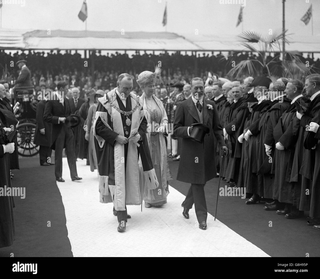 Re Giorgio V e la regina Maria sono accompagnati dal Lord Provost Sir Thomas Hutchinson, mentre hanno aperto la nuova centrale elettrica a Portobello. I membri della City Corporation sono allineati su entrambi i lati. Foto Stock