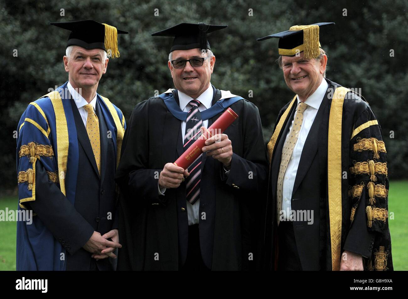 Christopher Norman (al centro) tiene il suo insigne scroll premio Fellowship con il Cancelliere dell'Università di lettura Sir John Madejski (a destra) e il vice-cancelliere Sir David Bell (a sinistra) dopo una cerimonia all'Università di Reading. Foto Stock