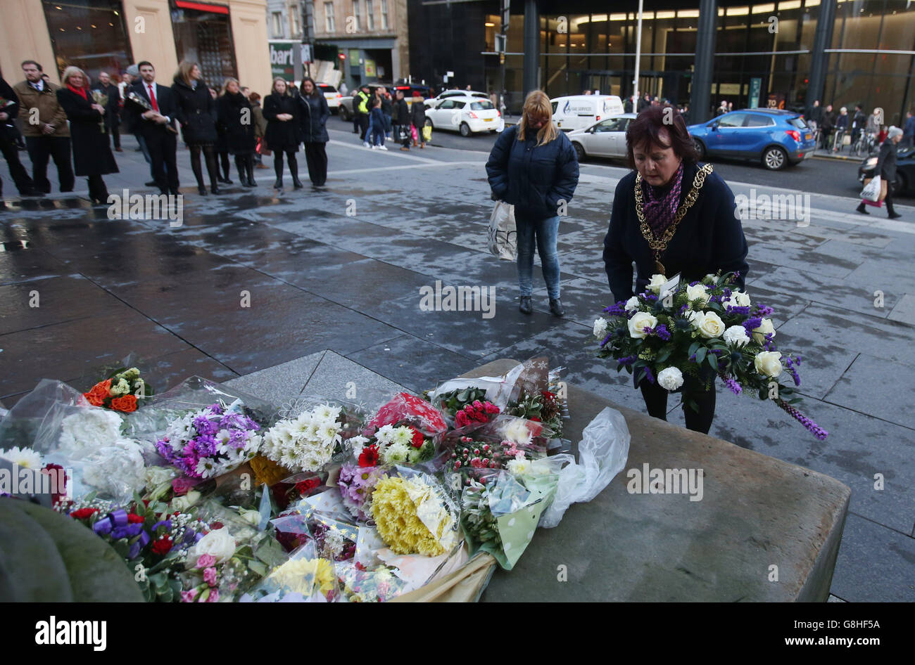 Lord Provost of Glasgow Sadie Dochrety depone fiori insieme ad altri tributi lasciati in Royal Exchange Square per celebrare l'anniversario del crollo dei camion a bin di Glasgow, che ha ucciso sei persone e ha ferito molte altre. Foto Stock