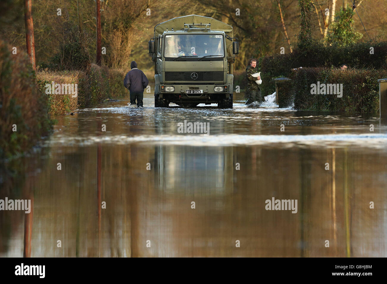 Un residente locale (a sinistra) passa un camion dell'esercito mentre i membri delle forze di difesa si impartiscono nell'area vicino a Springfield, nella contea di Clare, poiché le inondazioni sono previste per peggiorare nel corso del fine settimana. Foto Stock