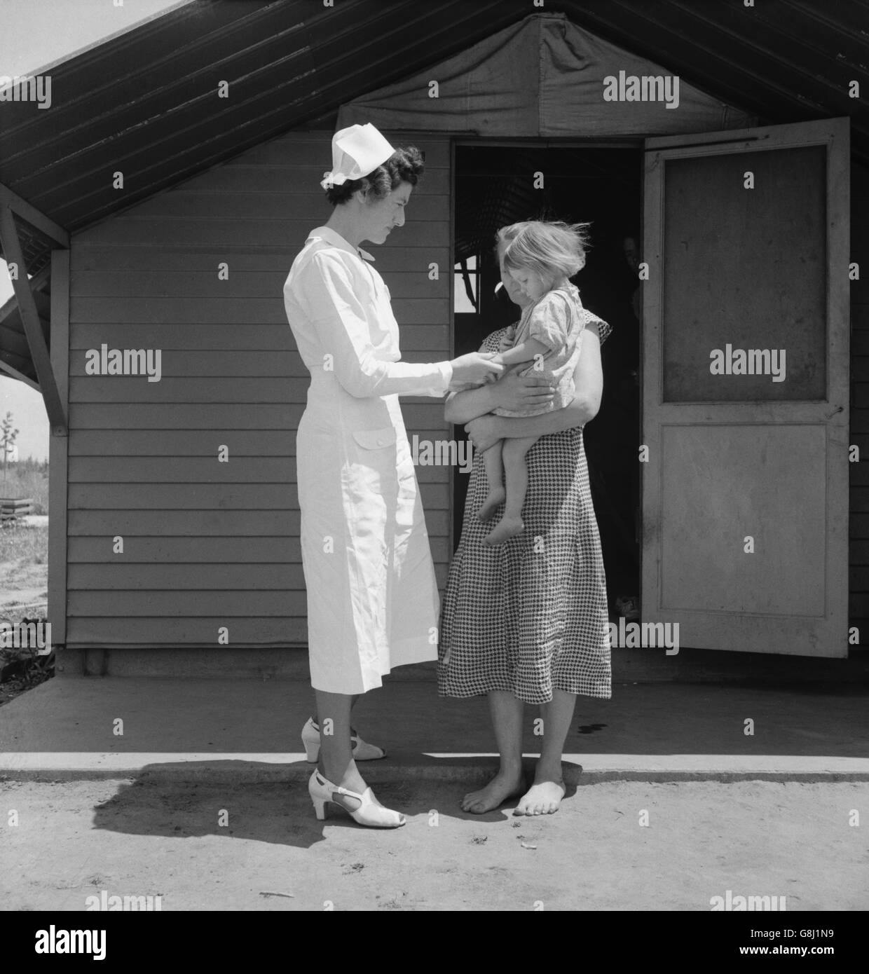 Infermiere residente in visita a un bambino malato, Farm Security Administration (FSA) Camp, Farmersville, Tulare County, California, USA, Dorothea Lange per la Farm Security Administration, Maggio 1939 Foto Stock