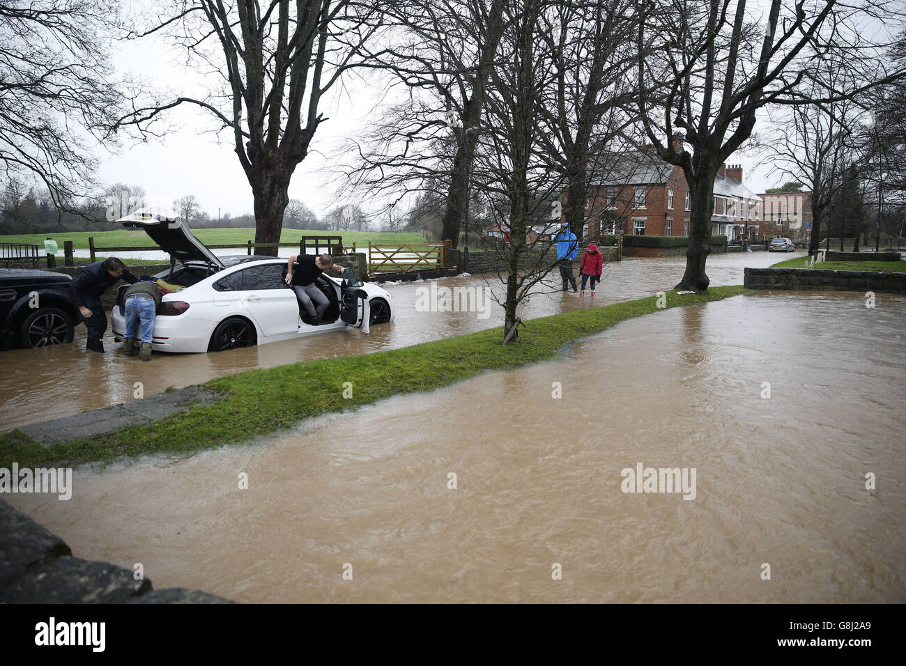 Gli automobilisti che passano aiutano il conducente di un'auto che si è arenata in acque alluvionali nel villaggio di Bishop Monkton, North Yorkshire. Foto Stock