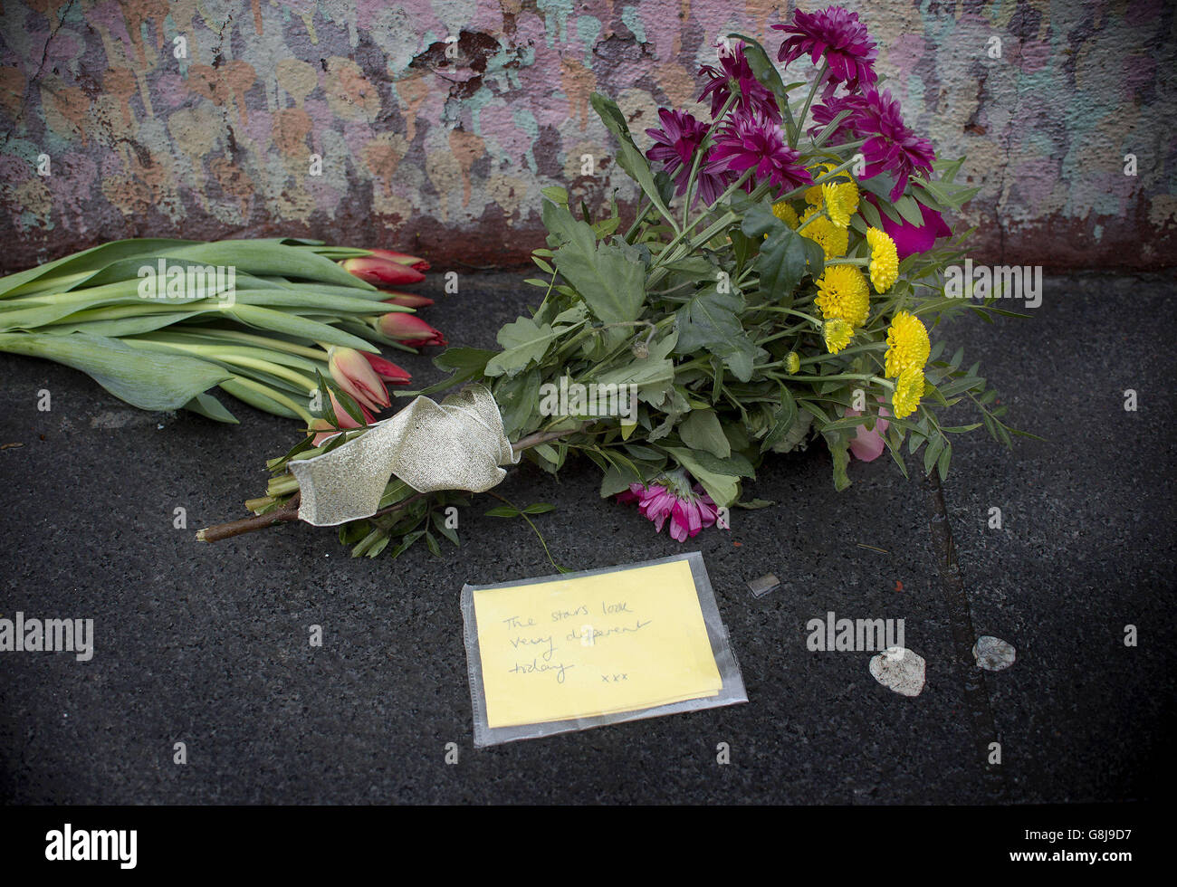 I fiori sono lasciati sotto un murale di David Bowie sul muro di un negozio di Morley a Brixton, Londra, il luogo di nascita dei cantanti, dopo la morte della rock star a seguito di una battaglia di 18 mesi con il cancro. Foto Stock