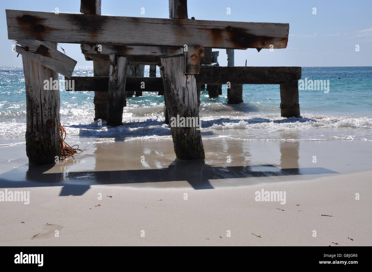 Abbandonato il pontile con ombre nel le acque dell'Oceano Indiano a Jurien Bay beach sotto un cielo blu in Western Australia. Foto Stock