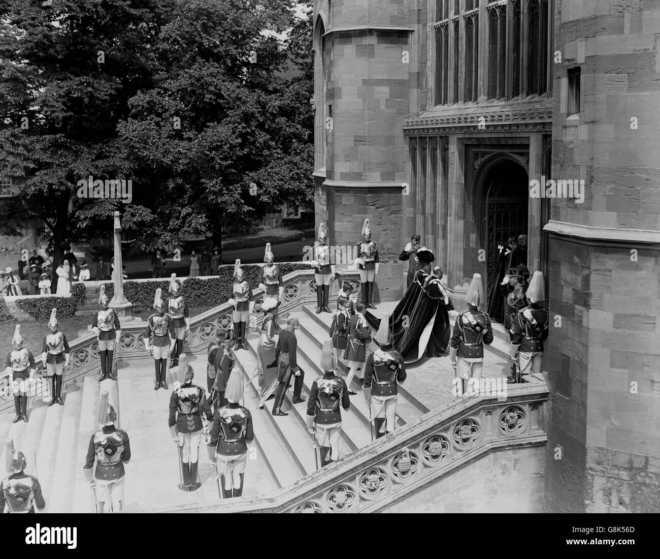 Re Giorgio V e la regina Maria vestiti in abiti a una cerimonia Garter a Windsor. Stanno salendo i gradini per entrare nella Cappella di San Giorgio. Foto Stock