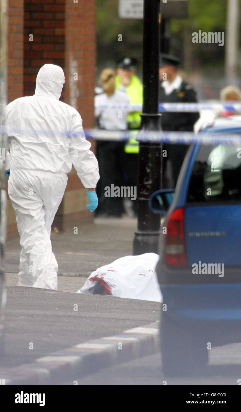 Un ufficiale PSNI ispeziona la scena dopo che un uomo è stato ucciso da paramilitari lealisti fuori dal negozio di Sandy Row. La vittima, chiamata Mick Green, è stata sgranata quando è arrivato su una moto per aprire il negozio Gilpin Furniture. Si ritiene che sia stato colpito diverse volte poco dopo le 8 del mattino. Foto Stock