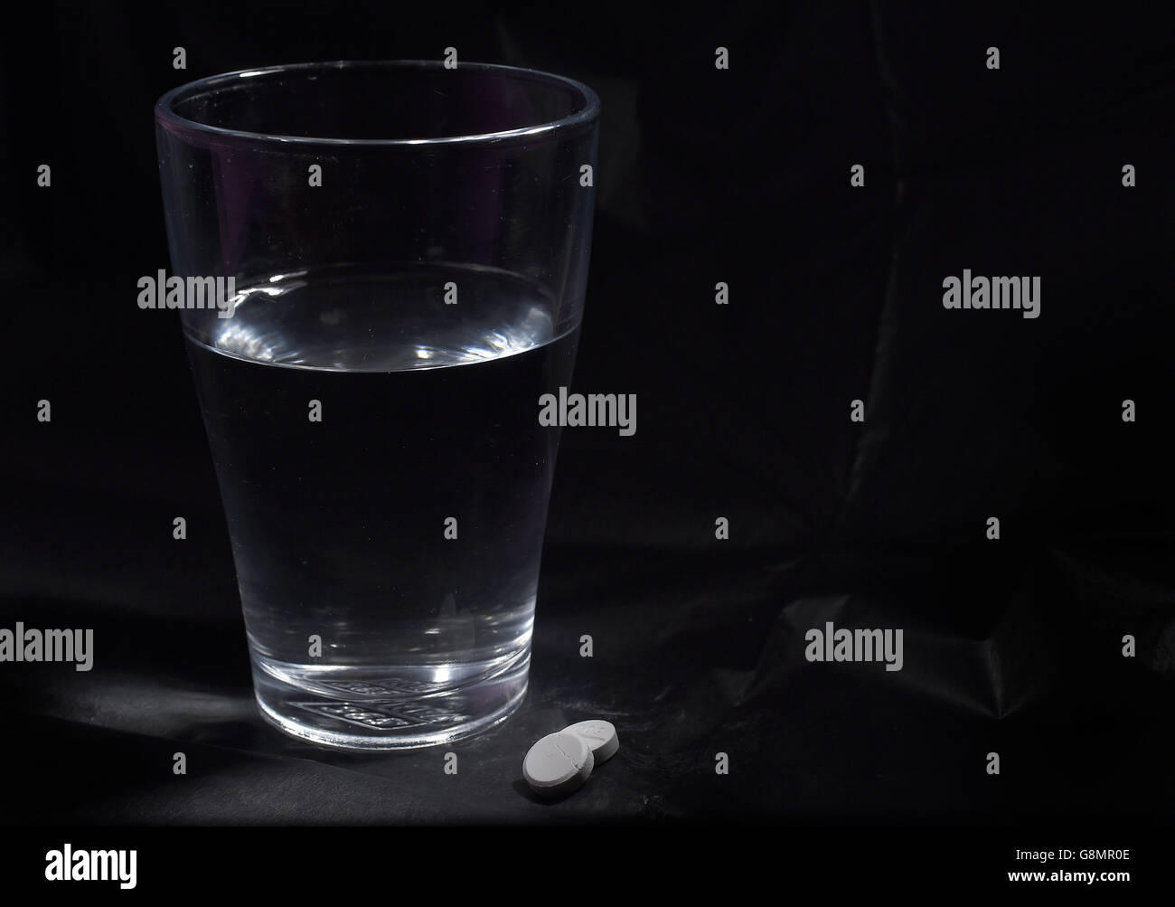 Scorta assassino di dolore. Foto di Ibuprofen e un bicchiere d'acqua. Foto Stock