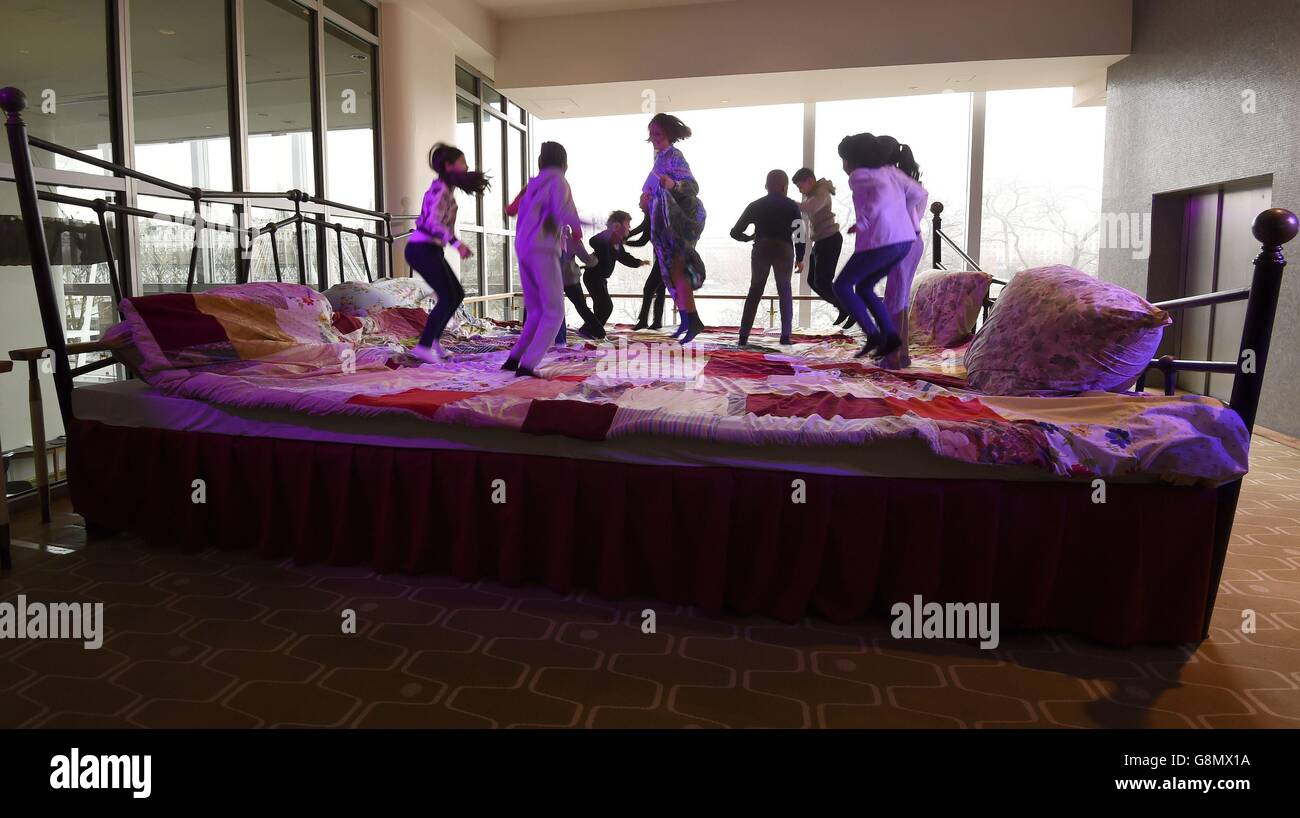 L'autrice per bambini Laura Dockrill e un gruppo di bambini salta sul "letto di narrazione gigante", un letto di 4x5 metri, durante il lancio del festival annuale Imagine Children's Festival del Southbank Centre al Southbank Centre, Londra, Che celebrerà il centenario di Roald Dahl, con una serie di eventi e installazioni a tema Roald Dahl. Foto Stock