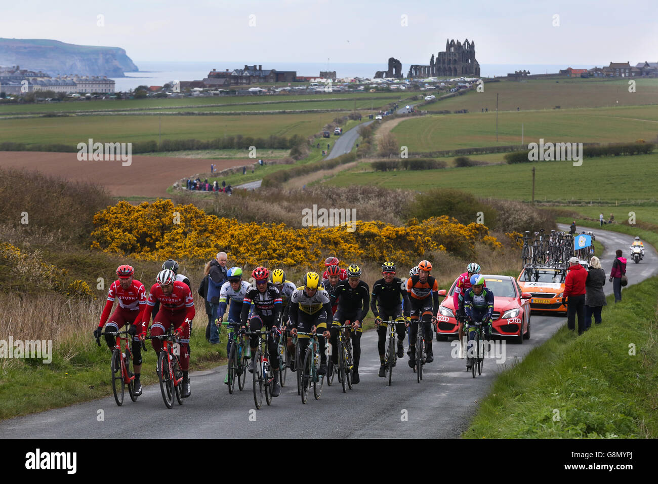 Il peloton, con la famosa abbazia dietro di loro, rende il modo fuori di Whitby nel finale di tappa del Tour de Yorkshire. Foto Stock