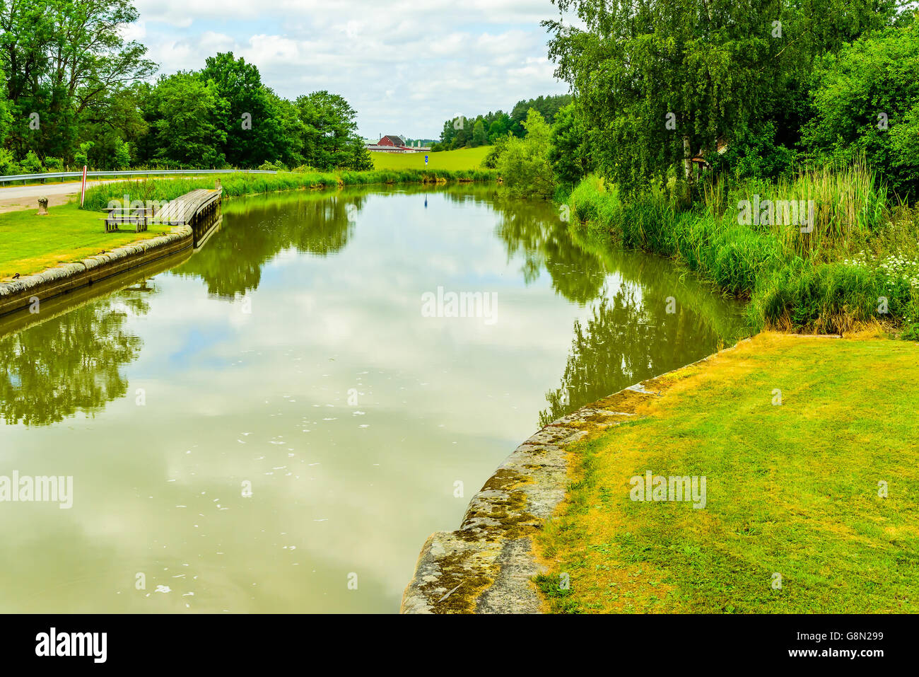 Il paesaggio lungo parte della Gota canal in Svezia con un ormeggio molo o pontile un argine e incantevole vegetazione sulle altre Foto Stock